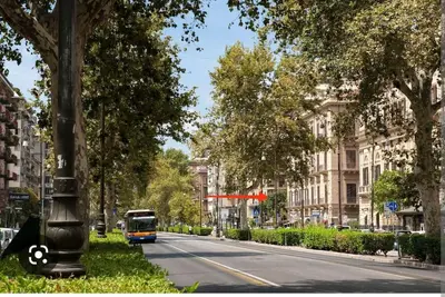a bus is driving down a city street with trees at Liberty Casa Mazzini 34 in Palermo