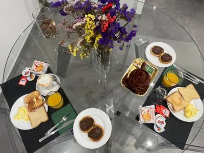 a glass table with plates of breakfast foods and a vase of flowers at Sant’Agostino Boutique Rooms in Palermo