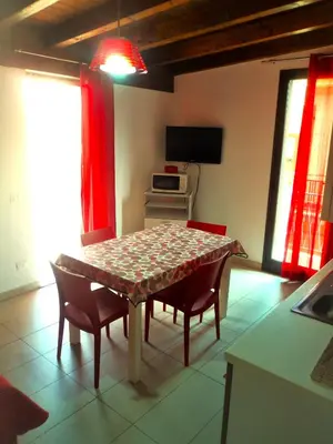 a dining room with a table and chairs and a television at Purple House a Castellammare del Golfo in Castellammare del Golfo