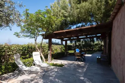 a patio with two chairs and a wooden at Villa Premiere immersa nel verde a Castelluzzo in Castelluzzo