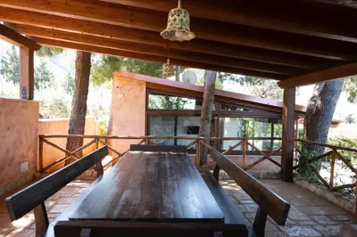 a wooden table sitting on a patio with trees at Villa Premiere immersa nel verde a Castelluzzo in Castelluzzo