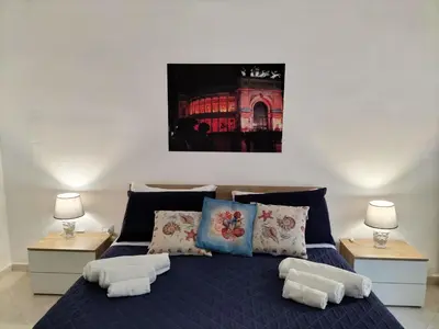 a bedroom with a blue bed with pillows and two lamps at InCentro Palermo in Palermo