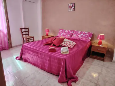 a bedroom with a pink bed with two tables and two lamps at DernaFlat 15 Climatizzata in Castellammare del Golfo