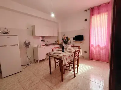 a kitchen with a table with chairs and a refrigerator at DernaFlat 15 Climatizzata in Castellammare del Golfo