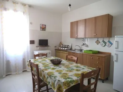 a kitchen with a table and a kitchen with a white refrigerator at Casa Derna 25dx Climatizzata in Castellammare del Golfo