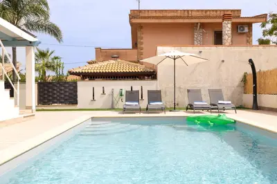 a swimming pool with two chairs and an umbrella at Villa Portofino - Private pool in Campofelice di Roccella