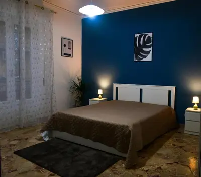 a bedroom with a bed and a blue wall at Amaryllis Apartments in Bagheria
