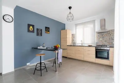 a kitchen with blue walls and a table and a stool at Villa Sikania Seaview Scopello in Castellammare del Golfo