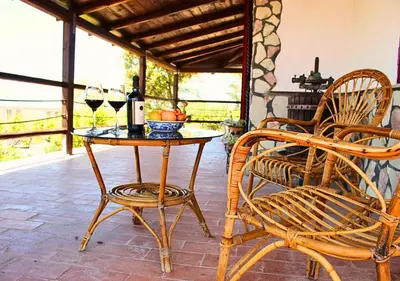 a patio with a table and two chairs and wine glasses at Villa Finestra sul Castello in Partinico