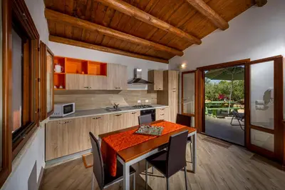 a kitchen with a wooden table and a dining room at Casetta degli Ulivi Castellammare del Golfo in Scopello