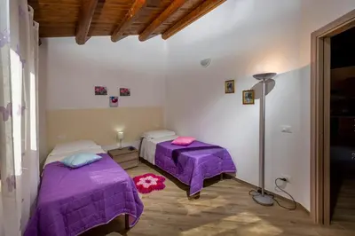 two beds in a room with purple sheets at Casetta degli Ulivi Castellammare del Golfo in Scopello