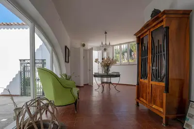 a living room with a table and a green chair at Villa Giacona Venuti in Terrasini