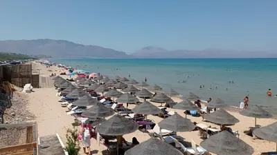 a beach with many umbrellas and people in the water at Casa Ventitré in Balestrate