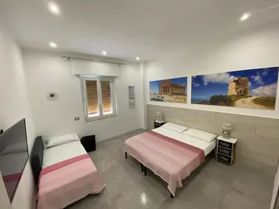 a bedroom with two beds and paintings on the wall at City Life in Palermo