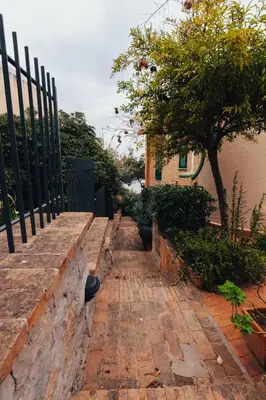 a brick pathway with a fence and a tree at Monia beach house in Santa Flavia