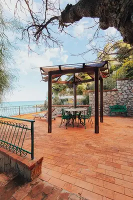 a picnic shelter with a table and benches next to the ocean at Monia beach house in Santa Flavia