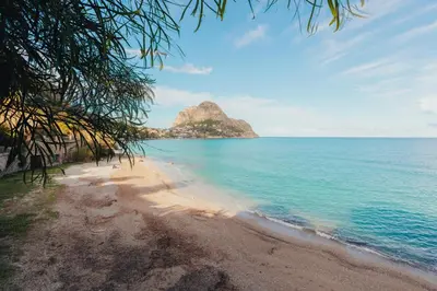 a beach with a rock in the middle of the ocean at Monia beach house in Santa Flavia