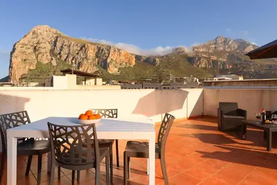 a table and chairs on a balcony with a mountain at Casa Serena in San Vito lo Capo