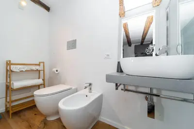 a white bathroom with a toilet and a sink at Casa Gagini in Palermo