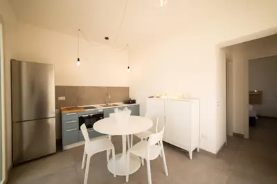 a kitchen with a table and chairs and a refrigerator at Blu Home Scopello in Castellammare del Golfo