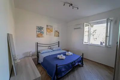 a bedroom with a bed with blue sheets and a window at Lovely Villa, close to the beach in Palermo
