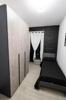 a bedroom with a bed and a brick wall at AVA VACATION HOME in Borgetto