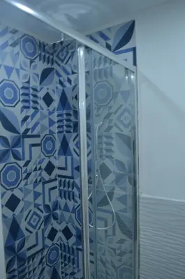 a shower in a bathroom with blue tiles at Palermo home cathedral apartment in Palermo