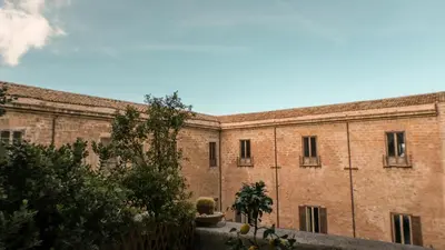a large brick building with trees in front of it at Donna Guia suite in Palermo
