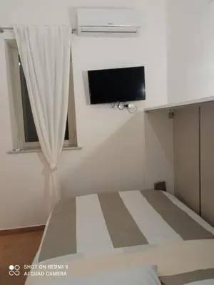 a bedroom with a bed with a curtain and a tv at Maqueda Suite Palermo at Cathedral in Palermo