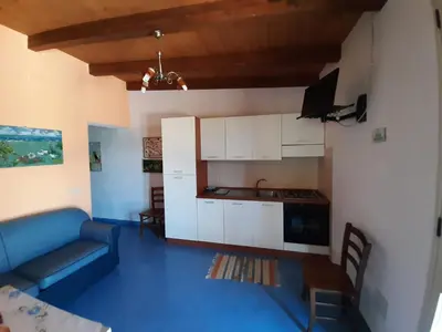 a living room with a blue couch and a kitchen at Villetta Edera all'Usciere in San Vito lo Capo