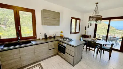 a kitchen with a stove and a table with chairs at Villa Felice - SEAVIEWS & PRIVATE POOL in Scopello