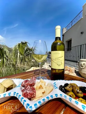 a bottle of wine and a plate of food and a glass at Villa Felice - SEAVIEWS & PRIVATE POOL in Scopello