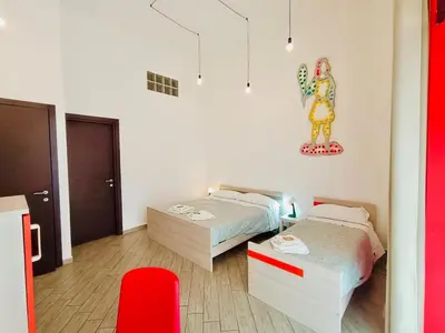 a bedroom with two beds and a red chair at Cortile dei Giusti - Combo Guesthouse in Palermo