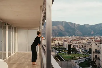 a woman standing on a balcony looking at a city at TOP OF THE PORT in Palermo