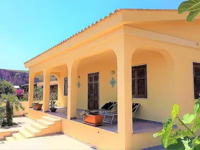 a small yellow house with a porch and stairs at Villa Contrada Sauci in San Vito lo Capo