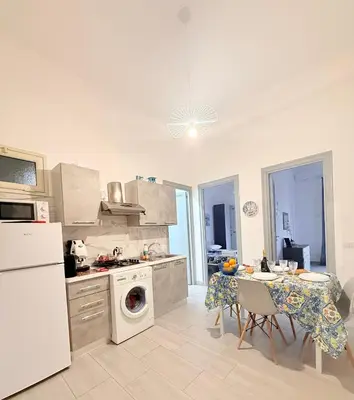 a kitchen with a white refrigerator and a table with chairs at Casa vacanza CUTÓ in Bagheria