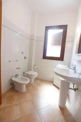 a bathroom with two sinks and a toilet and a window at SanVitoTour- Appartamento Smeraldo in San Vito lo Capo