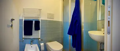 a blue tiled bathroom with a toilet and a sink at 38 HOUSE in Palermo