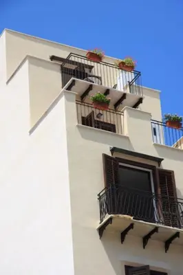 a white building with balconies and plants on it at A terrace in the heart of Palermo in Palermo