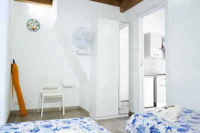 a bedroom with a bed and a chair and a clock at Meg Sicily House in Castellammare del Golfo