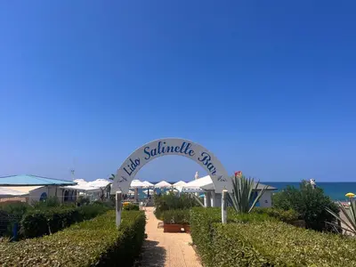a sign for a restaurant with umbrellas and bushes at Salinelle Rooms in Lascari