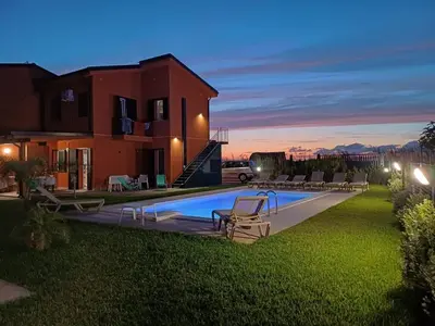 a villa with a swimming pool in front of a house at Salinelle Rooms in Lascari