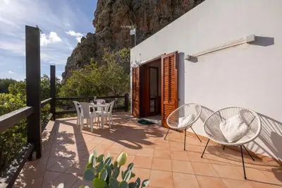 a patio with chairs and a table and a mountain at Pittalumari Makari in Macari