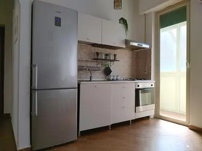a white kitchen with a refrigerator and a window at Appartamento Ai Murales in Palermo