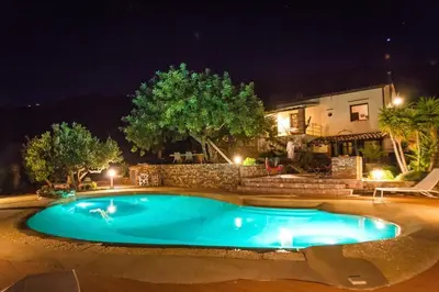a swimming pool in front of a house at night at Belle Vue Sarmuci in Scopello