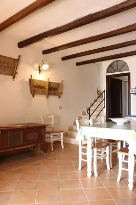 a living room with a table and chairs and stairs at Belle Vue Sarmuci in Scopello