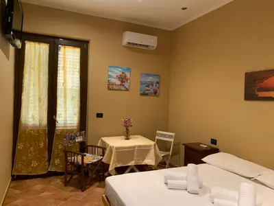 a room with two beds and a table and a window at Casa Alice in Isola delle Femmine