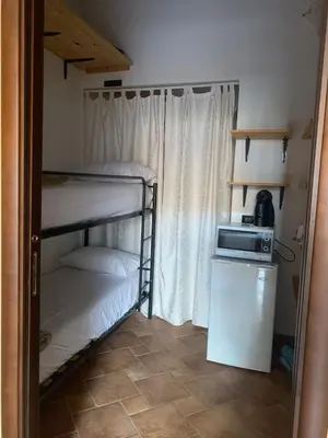 a small room with two bunk beds and a microwave at Casa Alice in Isola delle Femmine