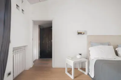 a white bedroom with a bed and a table at La Cala Terrace by Domusicily in Palermo