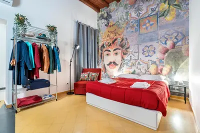 a bedroom with a red bed with a painting on the wall at CASA FLORIO in Palermo